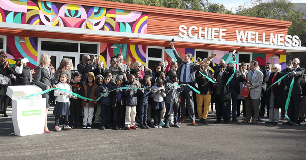 A group of kids and adults cheers as they cut the 