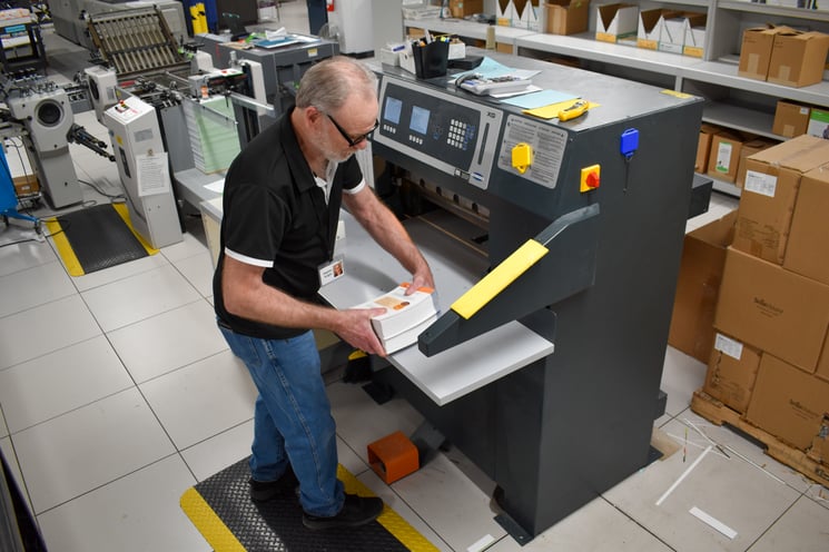 Man loads paper into a cutting and trimming machine