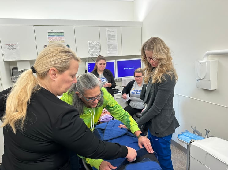 Group photo of an oral health care team learning how a papoose board works.