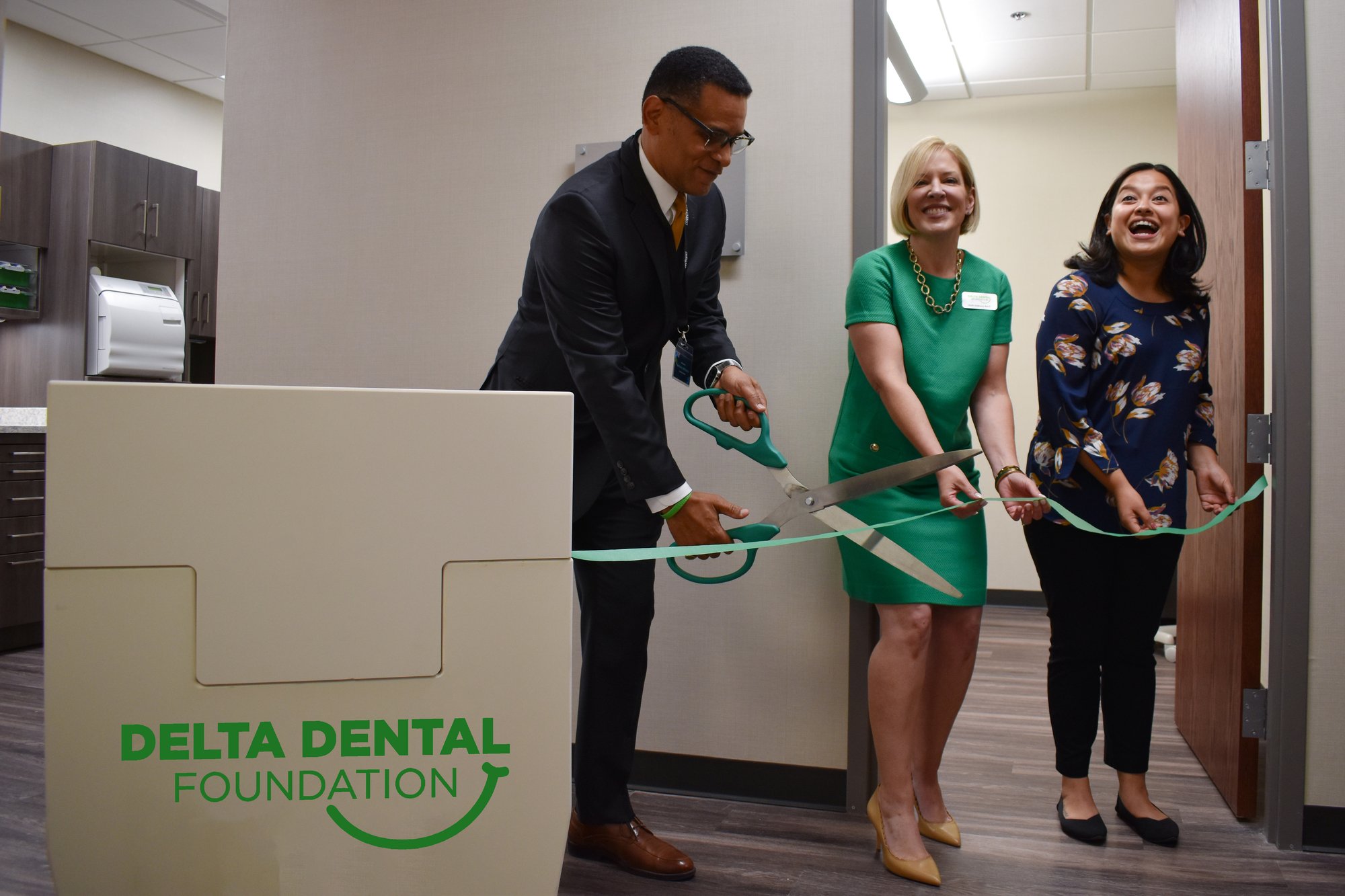 Anthony Williams, Holli Seabury, and Gabriela Santiago-Romero cut through a green ribbon of "floss" with big scissors and smiles.