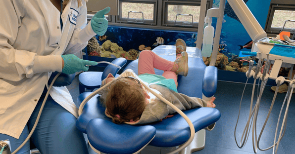 A young patient receives care from a dental intern.