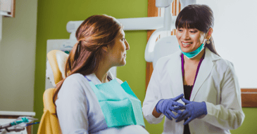 A female dentist provides dental education to a pregnant woman.